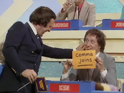 Image from classic British game show Blankety Blank with contestant Ken Dodd holding up a card with the answer 'comma joins'